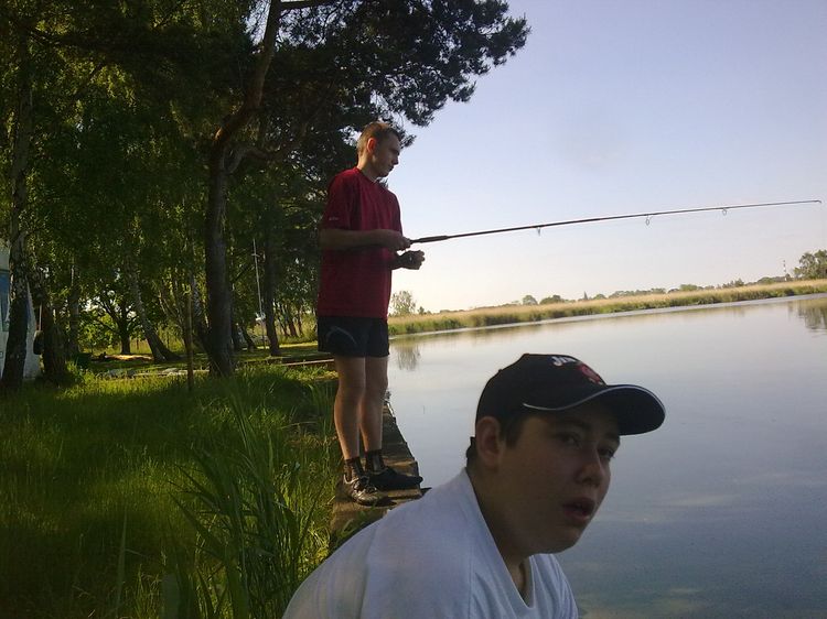 dwóch chłopaków nad jeziorem łowi ryby